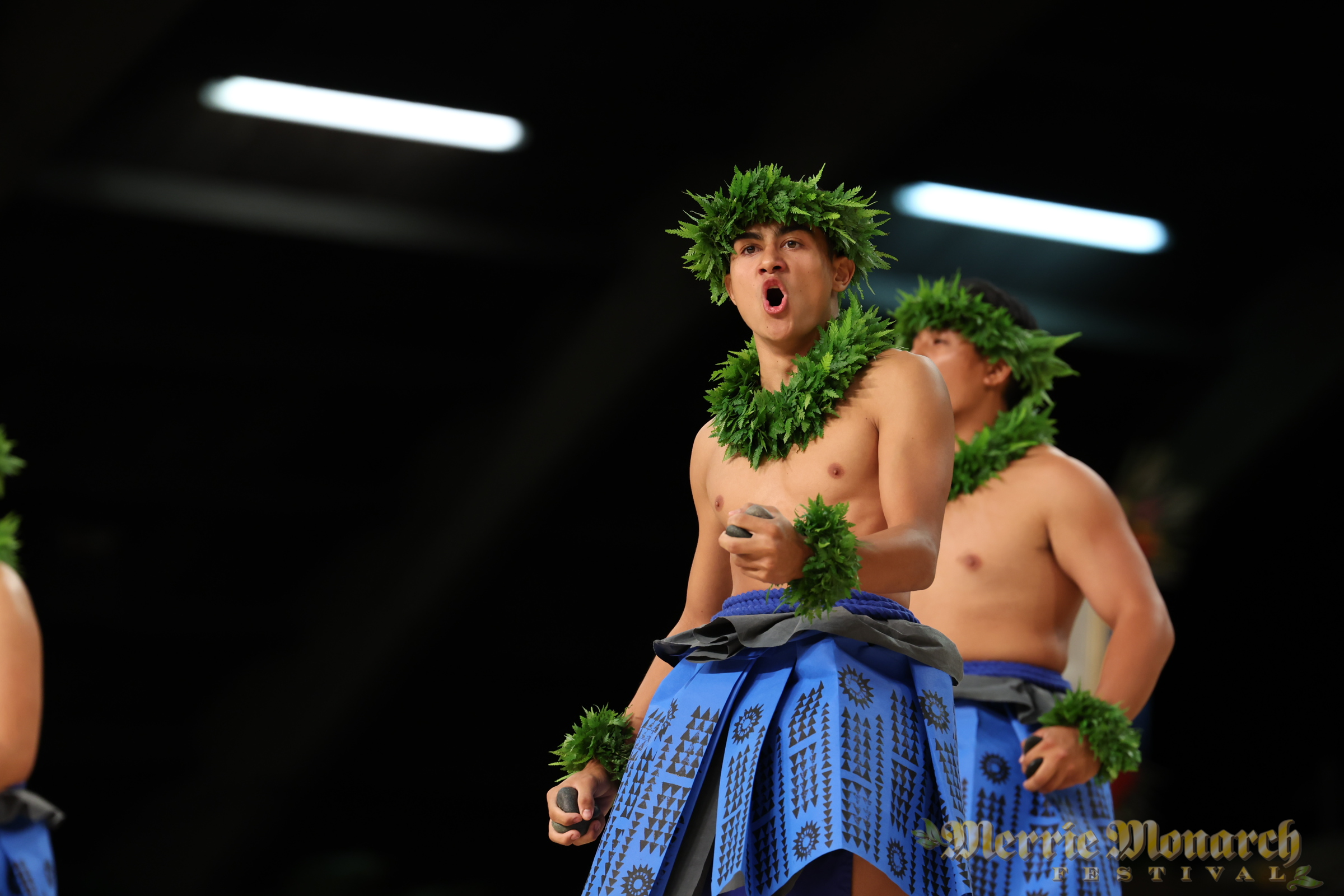 Kane chanting in blue patterns with ili'ili rocks in hand.