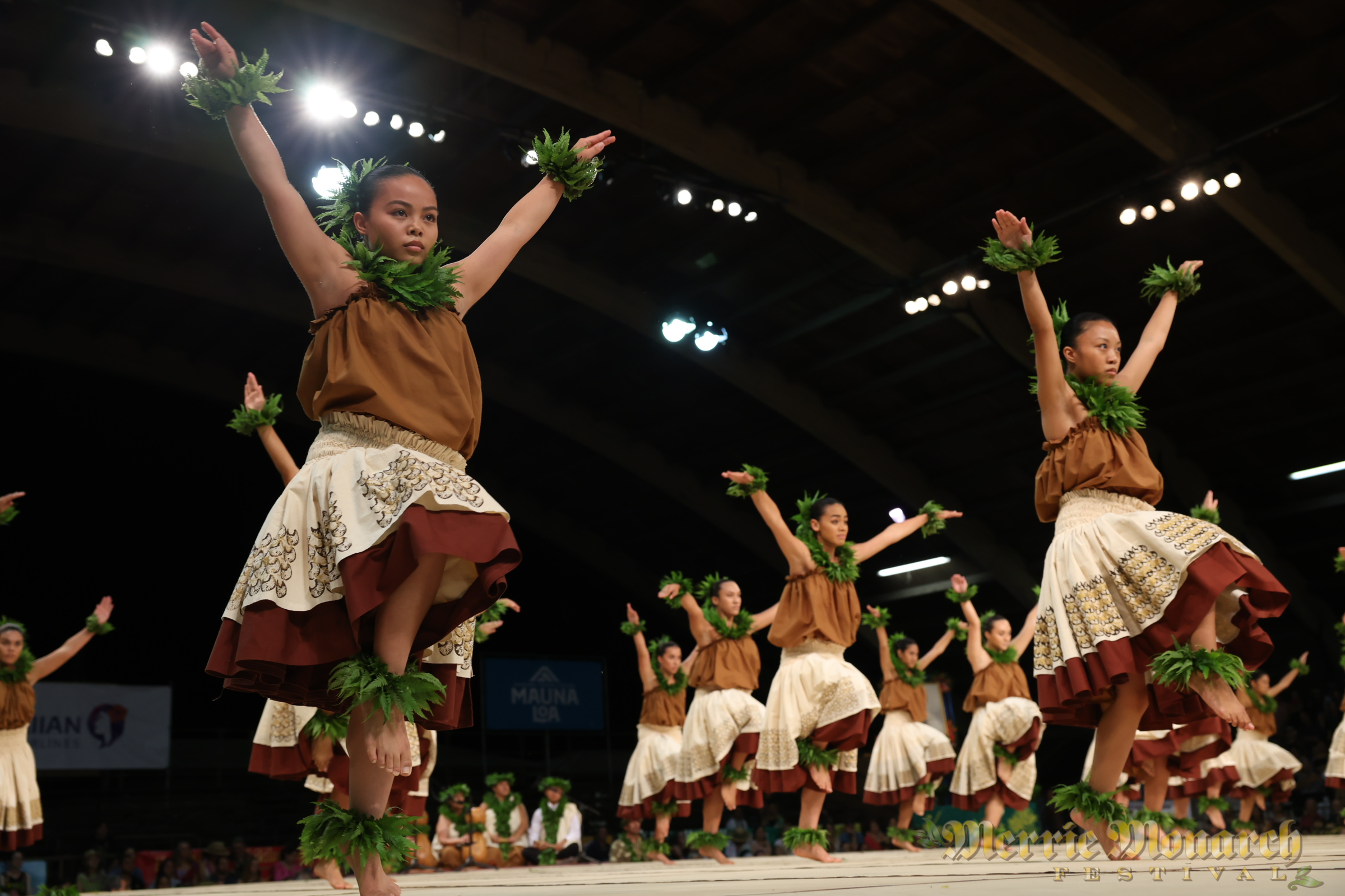 Stoic wahine wearing earth tones, dancing tribute to birds.